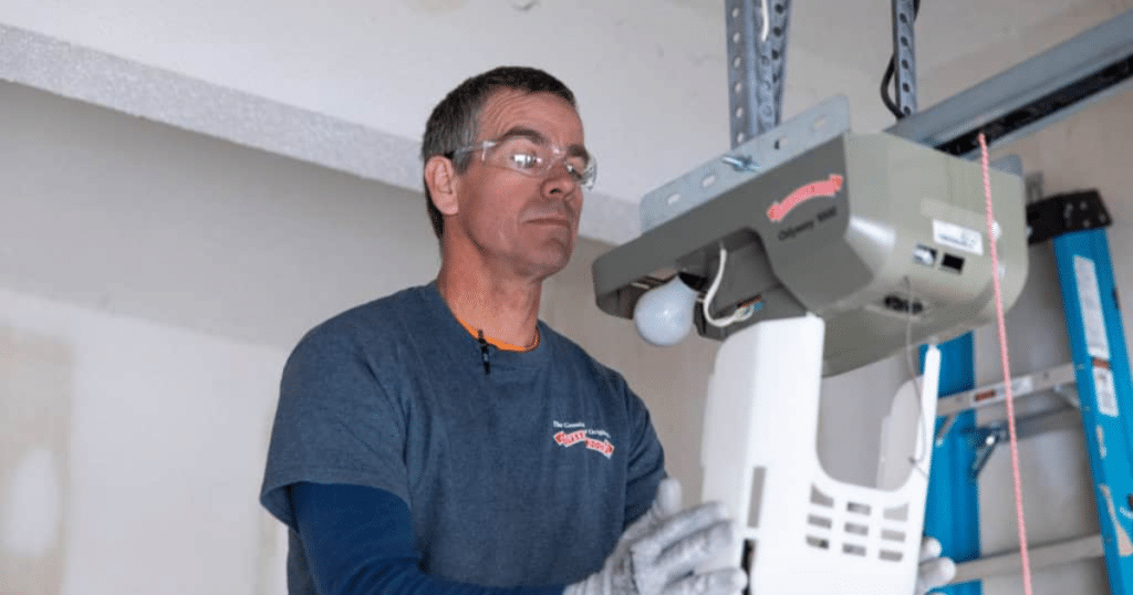 Technician in garage installing an overhead door opener.
