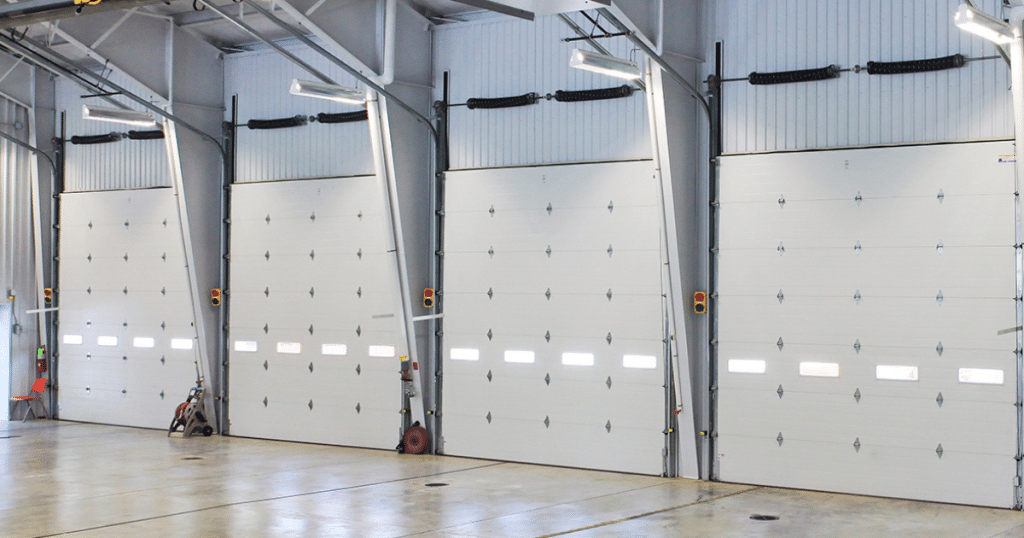 Multiple white garage doors inside an industrial building.