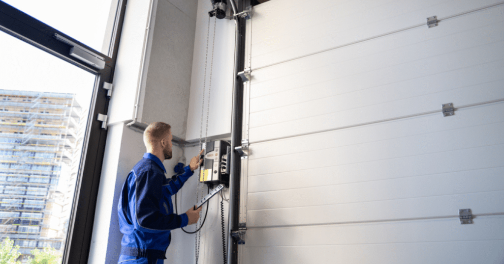 A technician adjusts a garage door opener on a white door.