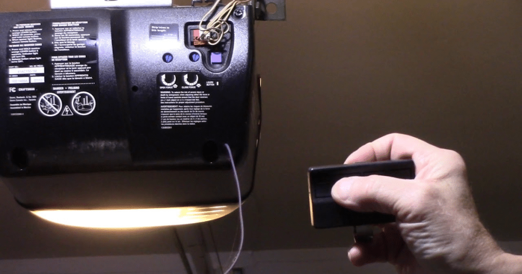 Hand holding remote near garage opener